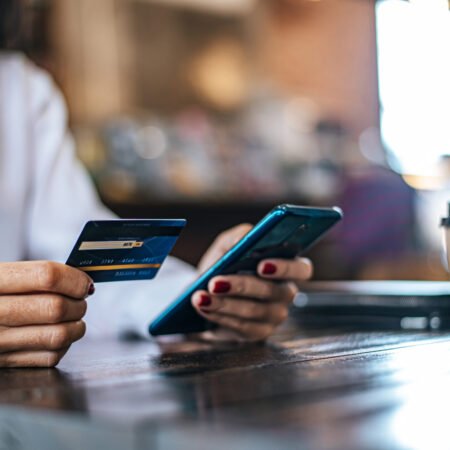 Pay for goods by credit card through a smartphone in a coffee shop.